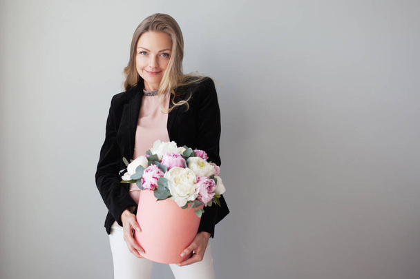 Charming blonde woman with flowers in a hat box. Bouquet of peonies. - Valokuva, kuva