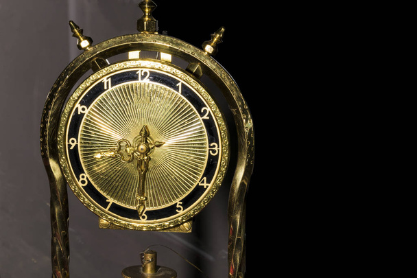 old metal desk clock of  gold color on a dark background with space for text - Photo, image