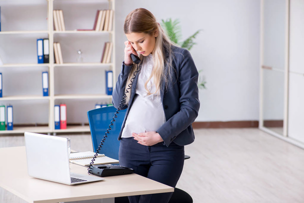 Pregnant woman employee in the office - Фото, изображение
