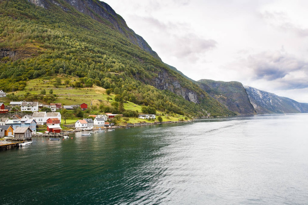 A Nærøyfjord, hegyek és a hagyományos falusi házak Norvégiában táj. - Fotó, kép