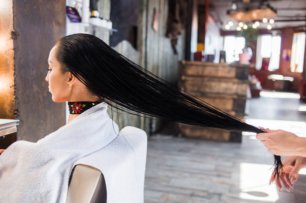 The hairdresser makes a Spa hair treatment for a woman brunette with long hair. Healthy well groomed hair. - Fotó, kép