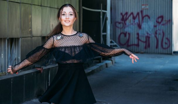 Emotional portrait of Fashion stylish portrait of pretty young woman. city portrait. sad girl. brunette in a black dress with stars and planets on a dress. expectation. dreams. beautiful brunette whirls around in the city. happy and cheerful. black d - Фото, изображение