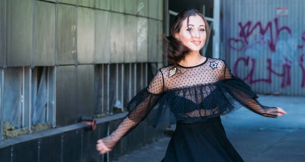 Emotional portrait of Fashion stylish portrait of pretty young woman. city portrait. sad girl. brunette in a black dress with stars and planets on a dress. expectation. dreams. beautiful brunette whirls around in the city. happy and cheerful. black d - Foto, imagen