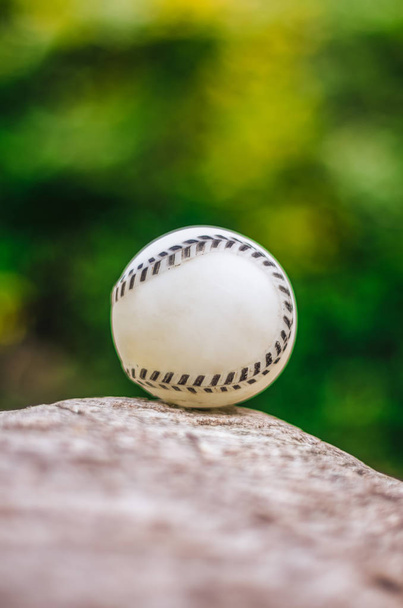 Бейсбол близко на скале, против зеленой растительности
 - Фото, изображение