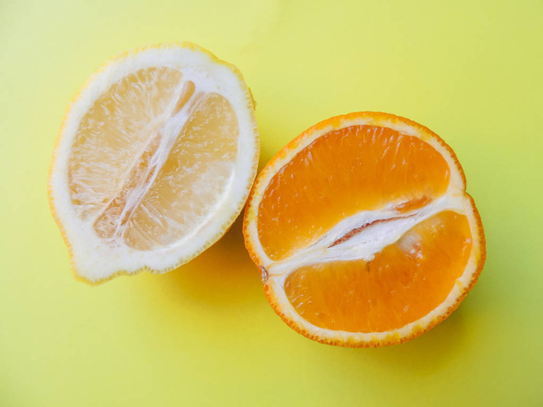 Orange and lemon close-up against a yellow background - Zdjęcie, obraz