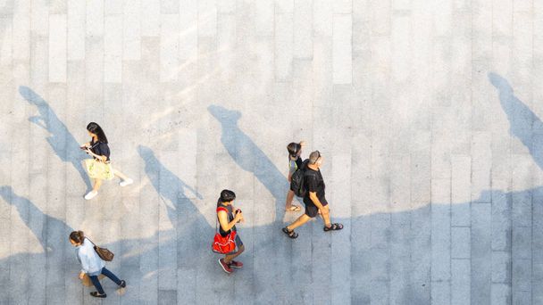 Толпа людей ходит по бетонному тротуару с высоты птичьего полета - Фото, изображение