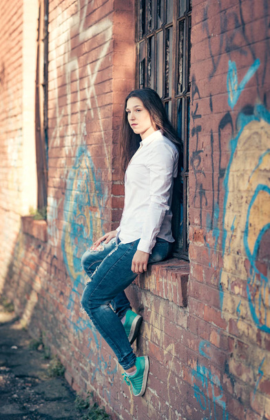 Portrait of beautiful female sitting on the wall,selective focus  - Zdjęcie, obraz