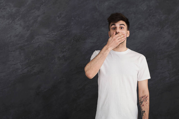 Sprachloser Mann bedeckt Mund vor grauem Studiohintergrund - Foto, Bild
