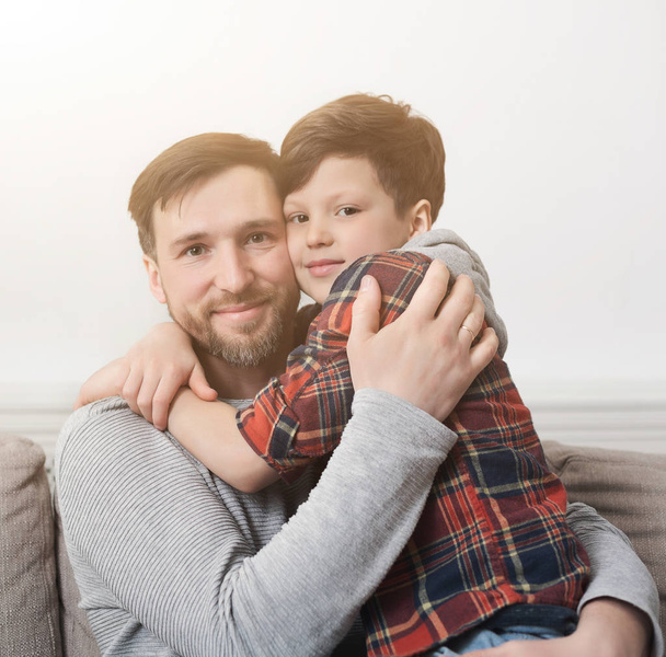 Apa és fia, átölelve a kanapén, otthon - Fotó, kép