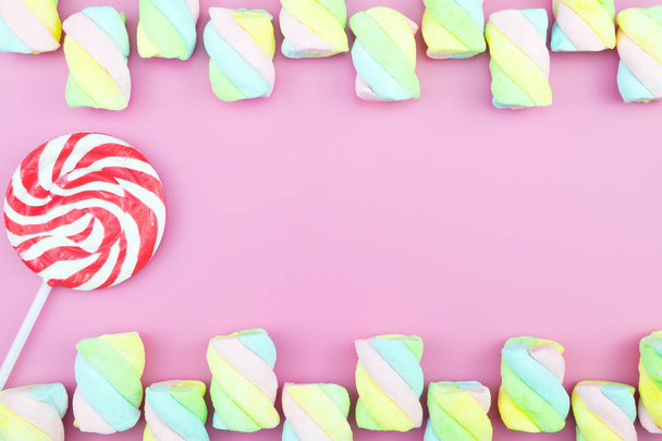 Lapos feküdt felülnézet ízletes étvágygerjesztő koncepció, minimális édes kezelésére örvény édességet nyalóka marshmallow színes minta rózsaszín pasztell háttér, és másolja a hely - Fotó, kép