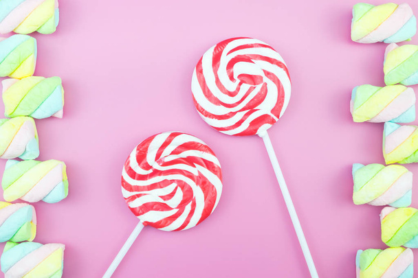 Plat leggen bovenaanzicht smakelijke smakelijk concept, minimale Sweet behandelen Swirl Candy Lollipop marshmallow kleurrijke patroon op roze pastel achtergrond en kopiëren van ruimte - Foto, afbeelding