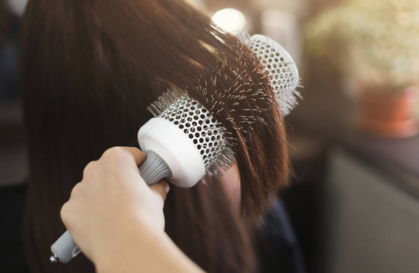Κομμώτρια που χτενίζει τα μαλλιά με κυλινδρική βούρτσα - Φωτογραφία, εικόνα