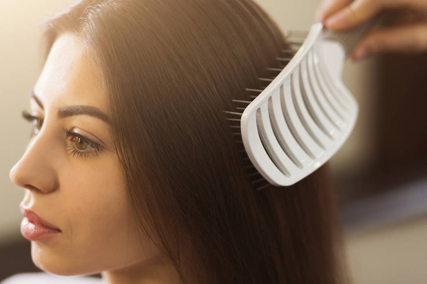 Стилист расчесывает волосы женщины в салоне
 - Фото, изображение