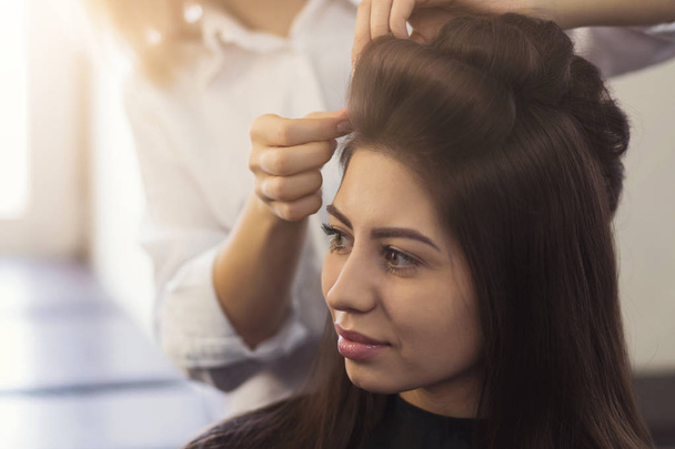 Hairstylist make curls on brown clients hair - Фото, зображення