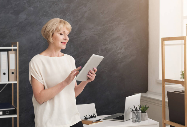 Nowoczesna kobieta interesu z cyfrowego tabletu w biurze - Zdjęcie, obraz