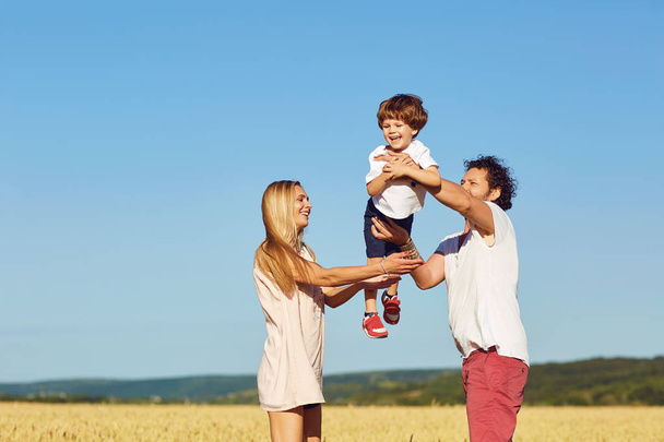A happy family is enjoying fun with a child outdoors. - Φωτογραφία, εικόνα