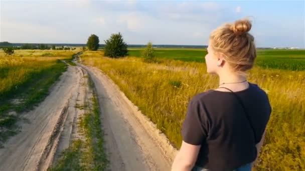 Das Mädchen läuft auf einer kurvenreichen Straße im Feld. Zeitlupe - Filmmaterial, Video