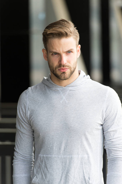 Macho in sweatshirt outdoor. Bearded man with serious face on fresh air. Taking a minute break. Casual in style. Sporty handsome - Foto, afbeelding