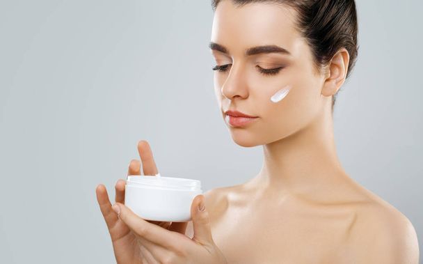 Beauty Concept. woman holds a moisturizer in her hand and spreads it on her face  to moisturize her skin and wrinkle from impurities. body care, skincare.Taking good care of her skin - Foto, Imagem