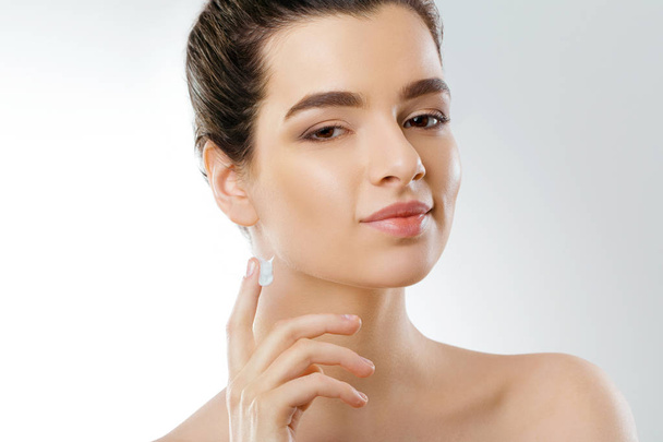 Facial Care. Female Applying Cream and Smiling. Portrait Of  Young Woman With Cosmetic Cream On Skin. Closeup Of Beautiful Girl With Beauty Product On Soft Skin, Natural Makeup Touching Face. High Resolution - Valokuva, kuva