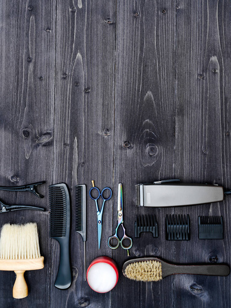 Hairdresser tools on wooden background. Top view on wooden table with scissors, comb, hairbrushes and hairclips, free space - Photo, image