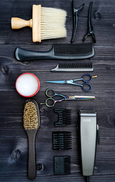 Hairdresser tools on wooden background. Top view on wooden table with scissors, comb, hairbrushes and hairclips, free space. Barbershop, manhood concept - Фото, изображение