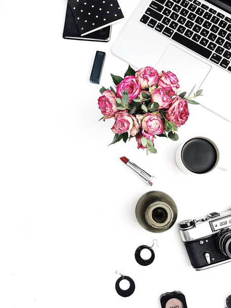 Frau Mode Home Office Schreibtisch. Arbeitsbereich mit Laptop, Rosenblütenstrauß, Retro-Kamera, Accessoires und Kosmetik auf weißem Hintergrund. flache Lage, von oben betrachtet stilvolle weibliche Attrappe. - Foto, Bild