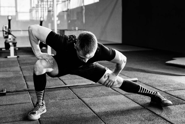 Young man preparing muscles before training. Muscular athlete exercising. Fit man stretching. Professional sportsman warming-up - Foto, afbeelding