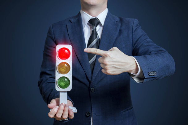 Businessman holding a traffic light with red light on. Business concept - Photo, Image