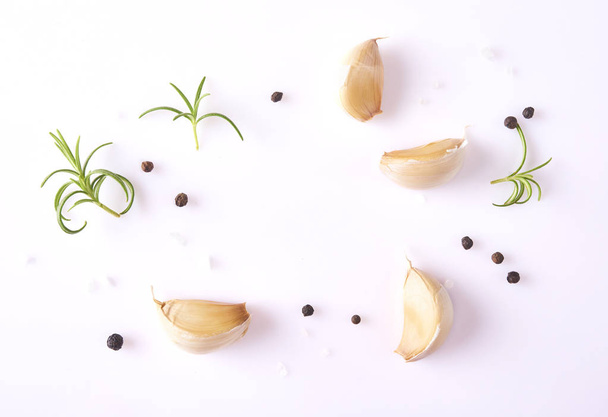 Concepto de comida. Composición con ajo fresco, hojas de romero y pimienta aislada sobre fondo blanco
 - Foto, Imagen