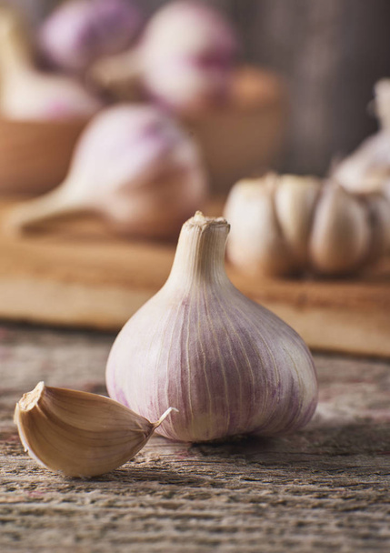 Close-up view of Raw Fresh garlic bulbs and cloves on cutting board over rustic wooden background - Valokuva, kuva