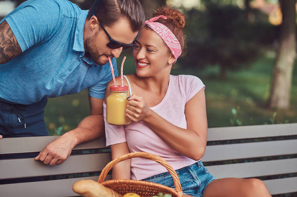 Szczęśliwy, średnim wieku para podczas randki, piknik na ławce w parku. - Zdjęcie, obraz