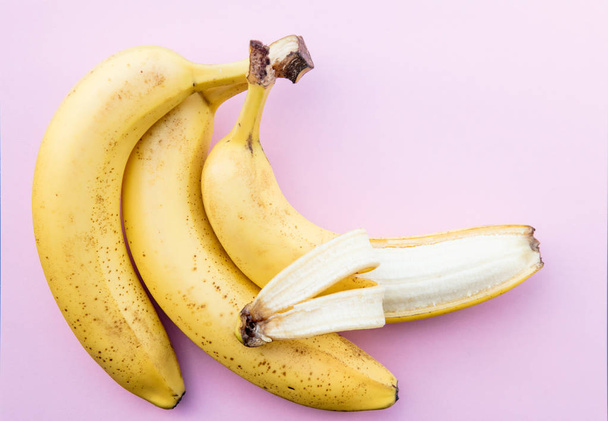 Yellow bananas on clear pink background - Foto, afbeelding