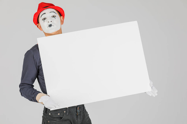 happy MIME artist holding a blank white Board, on a white background - Фото, изображение