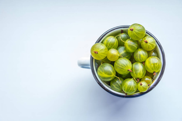 White cup Filled With Succulent Juicy Fresh Ripe Green Gooseberries On white background, Top view. Summer detoz food concept. copy space. - Photo, Image