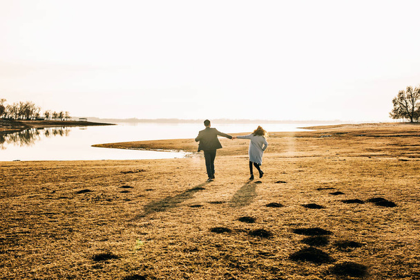 casal feliz correndo ao longo da praia ao pôr do sol
 - Foto, Imagem