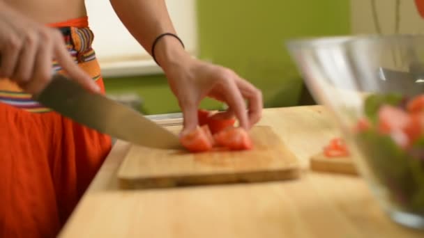 Close-up of a girl cuts a tomato wooden table for a salad of green tomatoes lemon and cheese - Footage, Video