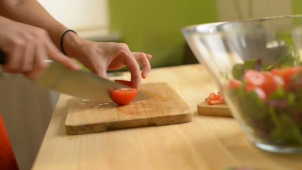 Close-up of a girl cuts a tomato wooden table for a salad of green tomatoes lemon and cheese - Záběry, video