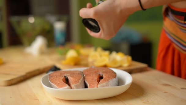 Szczegół dziewczyna skrapia stek z łososia z obu stron z ziół przed smażenia - Materiał filmowy, wideo