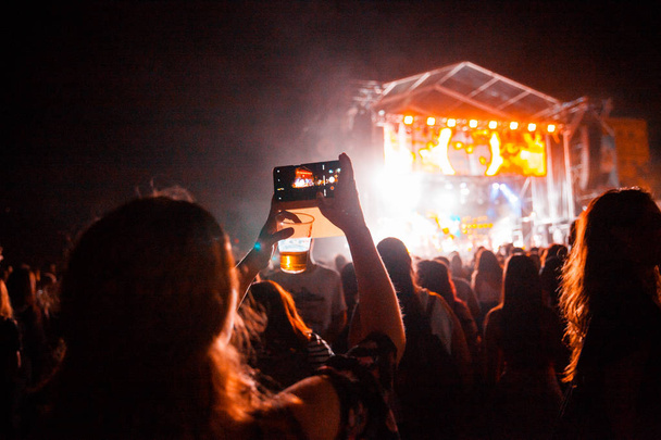 Veduta di un concerto con le persone stanno scattando foto, mani in alto e applaudendo a un festival musicale. Festival di musica estiva
. - Foto, immagini