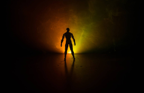 Silhouette dell'uomo in piedi su uno sfondo scuro nebbioso tonica. Foto decorata con figura uomo sul tavolo con luce. Focus selettivo
 - Foto, immagini