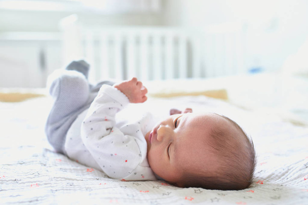 Чарівна новонароджена дівчинка лежить на ліжку батьків вдома
 - Фото, зображення