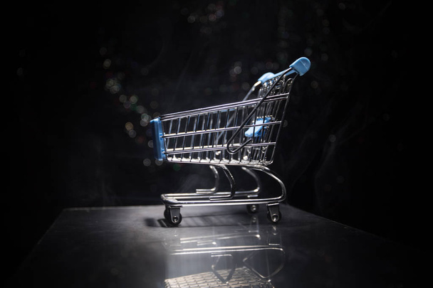 Empty shopping trolley on dark toned foggy background with some copy space. Financial crisis concept. - Foto, imagen