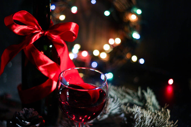 two red wine glass against christmas lights decoration background, eve of christmas. - Photo, Image