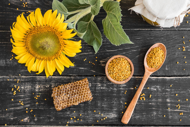 Beautiful transparent honey in bank, honeycombs and pollen on a wooden table. It can be used as a background - Photo, Image