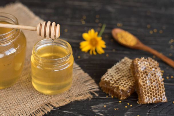 Красивый прозрачный мед в банке, соты и пыльца на деревянном столе. Его можно использовать в качестве фона
 - Фото, изображение