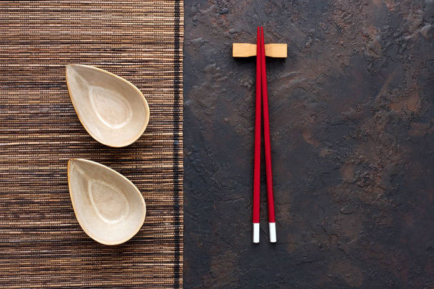 Top view of red chopsticks and  ceramic  bowl on concrete  background. Flat lay with copy space - Photo, image