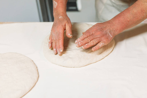 Baker is preparing dough for pizza in a traditional Bakery. - Foto, Imagem