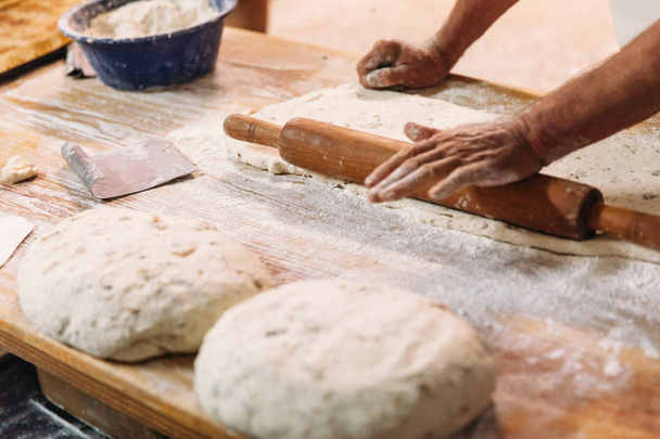 Male baker prepares bread. Baker kneading the dough with flour. Making bread. Rustic and traditional style of Bakery. - Φωτογραφία, εικόνα