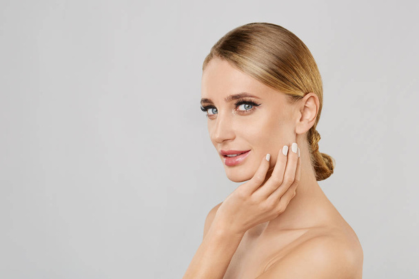 Portrait of smiling beautiful blonde woman with natural make up touching her face. Beauty young woman with fresh clean perfect skin. Skin care concept. Cosmetology,beauty and spa. Facial treatment. - Photo, Image